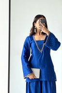 Woman taking a mirror selfie wearing a blue traditional outfit with intricate designs.