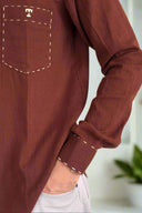 Brown long-sleeve shirt with white stitching on a beige background