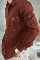 Brown shirt with a pocket and white pants on a plain background