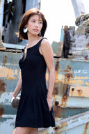 Woman in a black dress standing in front of a rusty metal background