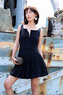 Woman in a black dress standing in front of a rusted metal background