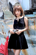 Woman in a black dress holding a red umbrella against a rusty metal background