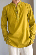 Yellow kurta with white pants on a plain background