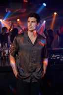 Man standing in a nightclub with colorful lights and people in the background