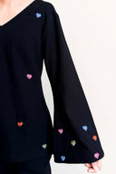 Black sweater with colorful heart patterns on a white background