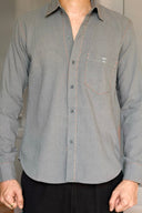 Person wearing a gray button-up shirt with a collar indoors.