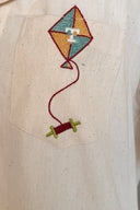 Embroidered kite design on a beige fabric background