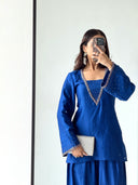 Woman taking a mirror selfie wearing a blue traditional outfit with intricate designs.