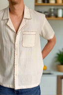 White short-sleeve shirt with decorative trim on a neutral background