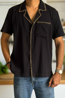 Black short-sleeve shirt with decorative stitching on a white background