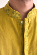 Close-up of a mustard yellow kurta with green embroidery on the collar and chest.