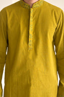 Mustard yellow kurta with intricate embroidery on a plain background