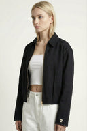 Woman wearing a black jacket over a white top and pants on a white background