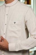 Close-up of a white embroidered shirt with a pocket on a plain background