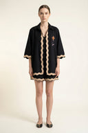 Woman wearing a black dress with beige trim on a white background