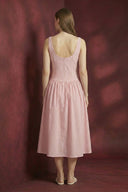 Woman wearing a pink striped dress against a maroon background