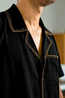 Black shirt with gold embroidery on a blurred background