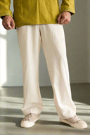 Person wearing a green jacket and white pants standing on a gray floor.