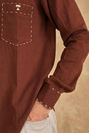 Brown long-sleeve shirt with a pocket detail on a beige background
