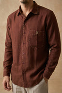 Brown button-up shirt worn by a person on a beige background