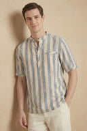 Man wearing a striped shirt with a logo against a beige background