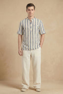 Man wearing a striped shirt and beige pants against a beige background