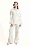 Woman wearing a white pajama set with colorful heart patterns on a white background